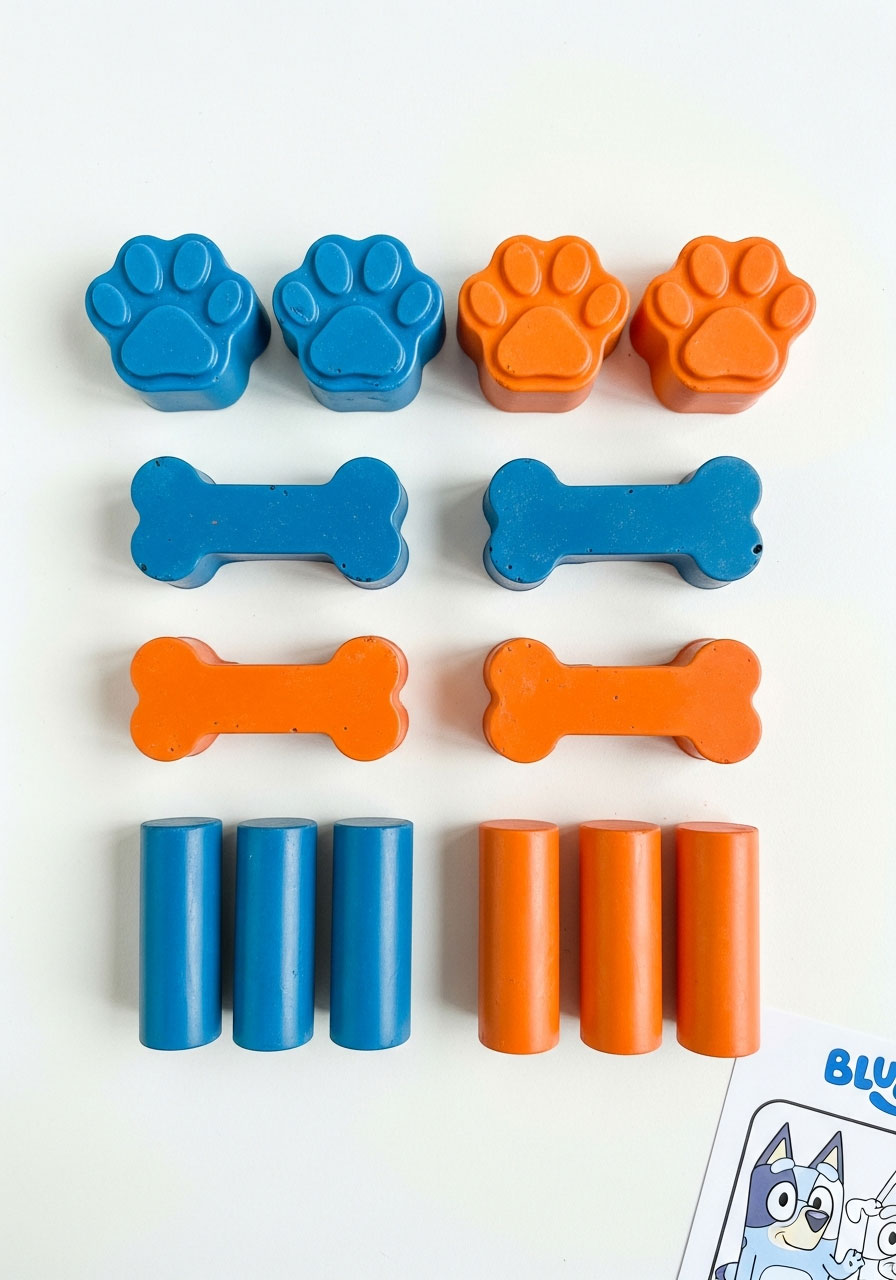 Dog paw and bone shaped crayons in blue and orange colors for Bluey birthday party favors