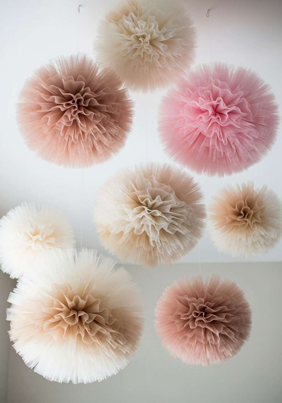 Soft tulle pom poms in blush and ivory hanging from ceiling - elegant DIY birthday party decoration