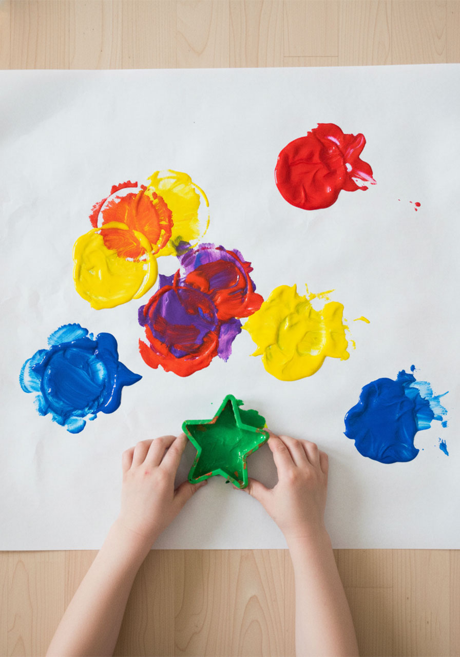 Overhead view of cookie cutter painting showing primary colors mixing to create secondary colors through overlapping stamps