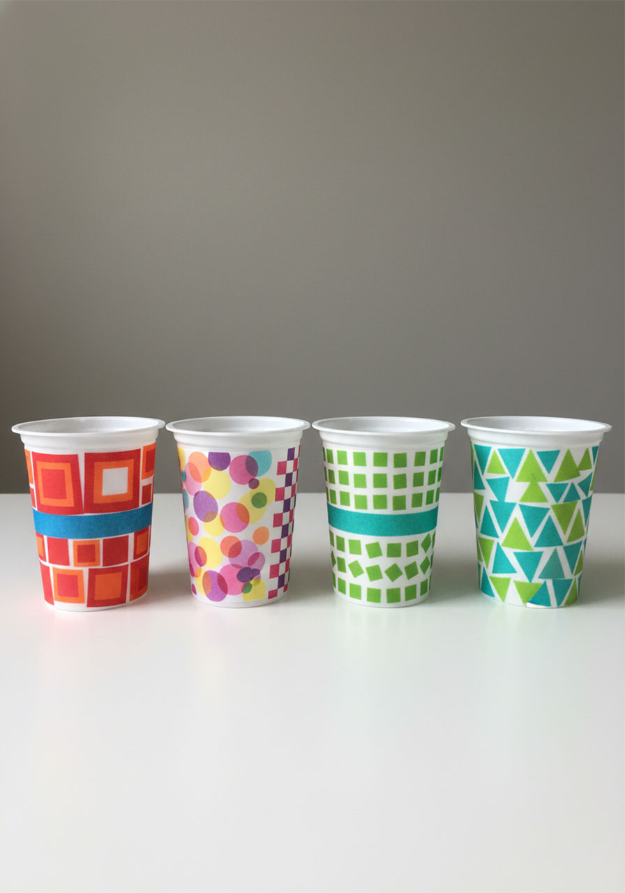 Four completed tissue paper lanterns with geometric patterns made from upcycled containers shown in daylight before adding LED lights