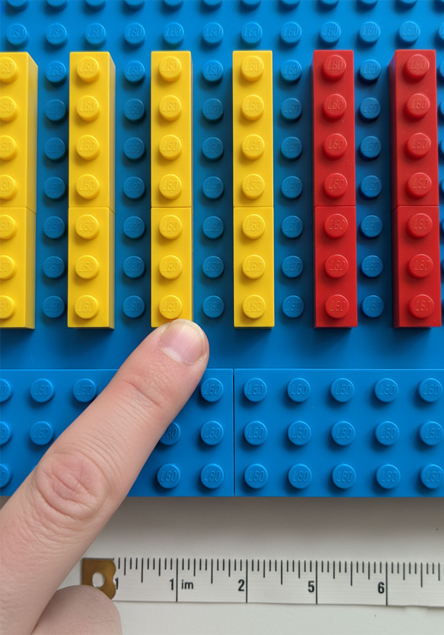Close-up of LEGO Plinko board bottom showing prize slots with 1x6 bricks spaced 3 studs apart