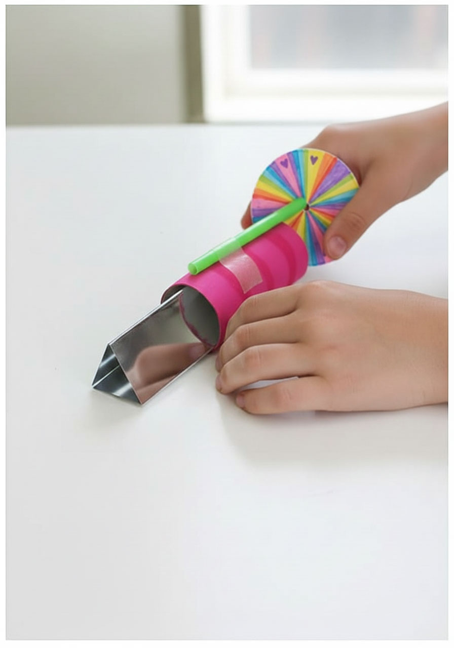 Final assembly step showing decorated circle being attached to bendy straw on completed kaleidoscope tube