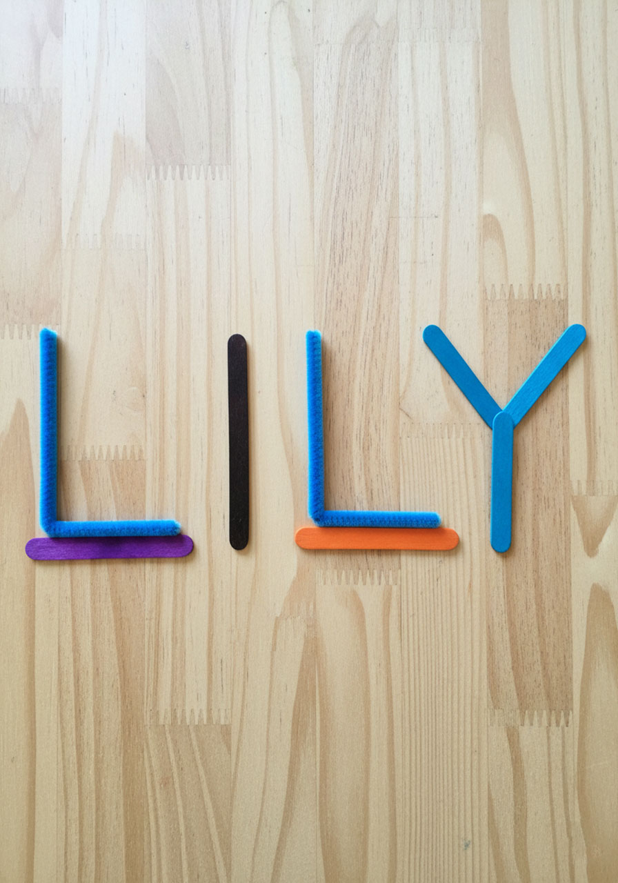 Name Lily spelled using blue pipe cleaners and colorful craft sticks demonstrating letter formation in kindergarten STEM activity