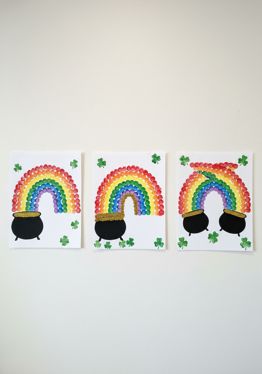 Three different completed fingerprint rainbow pot of gold crafts showing creative variations for St. Patrick's Day