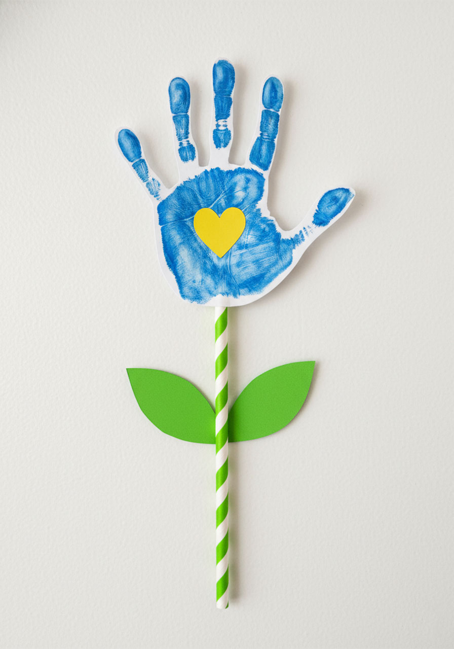 Single assembled Mother's Day handprint flower with green paper straw stem, leaves, and yellow heart center
