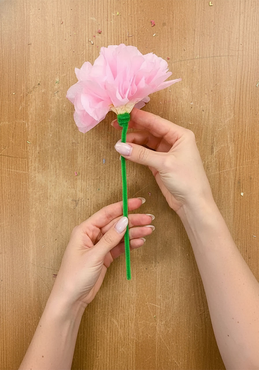 Wrapping a green pipe cleaner tightly around the base of a coffee filter flower to form the stem step 6b