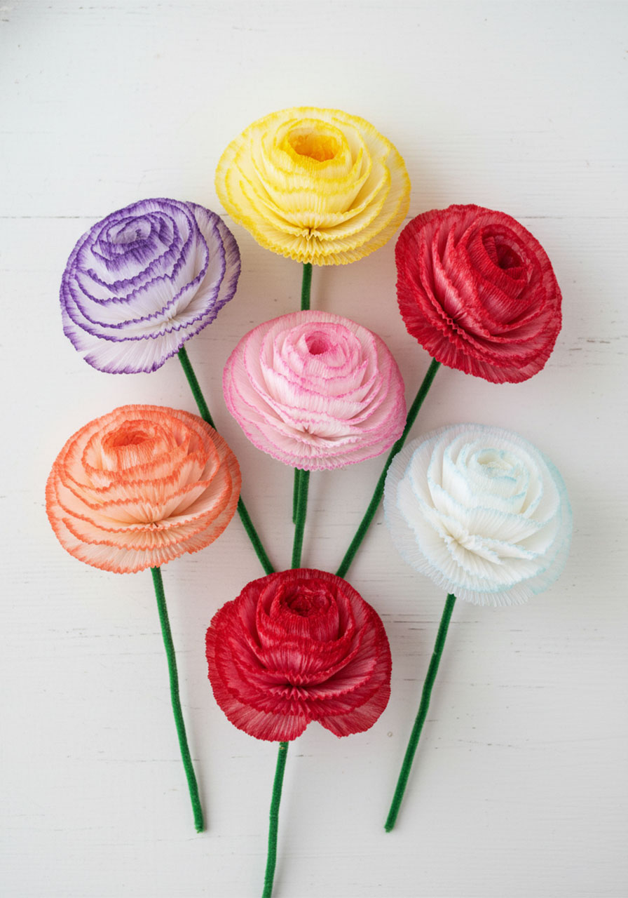 Six coffee filter flowers in different watercolor color combinations including pink, lavender, coral, and yellow