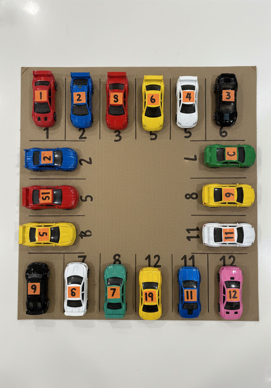 All 12 numbered Matchbox cars correctly parked in matching spots on a completed DIY preschool parking lot math activity