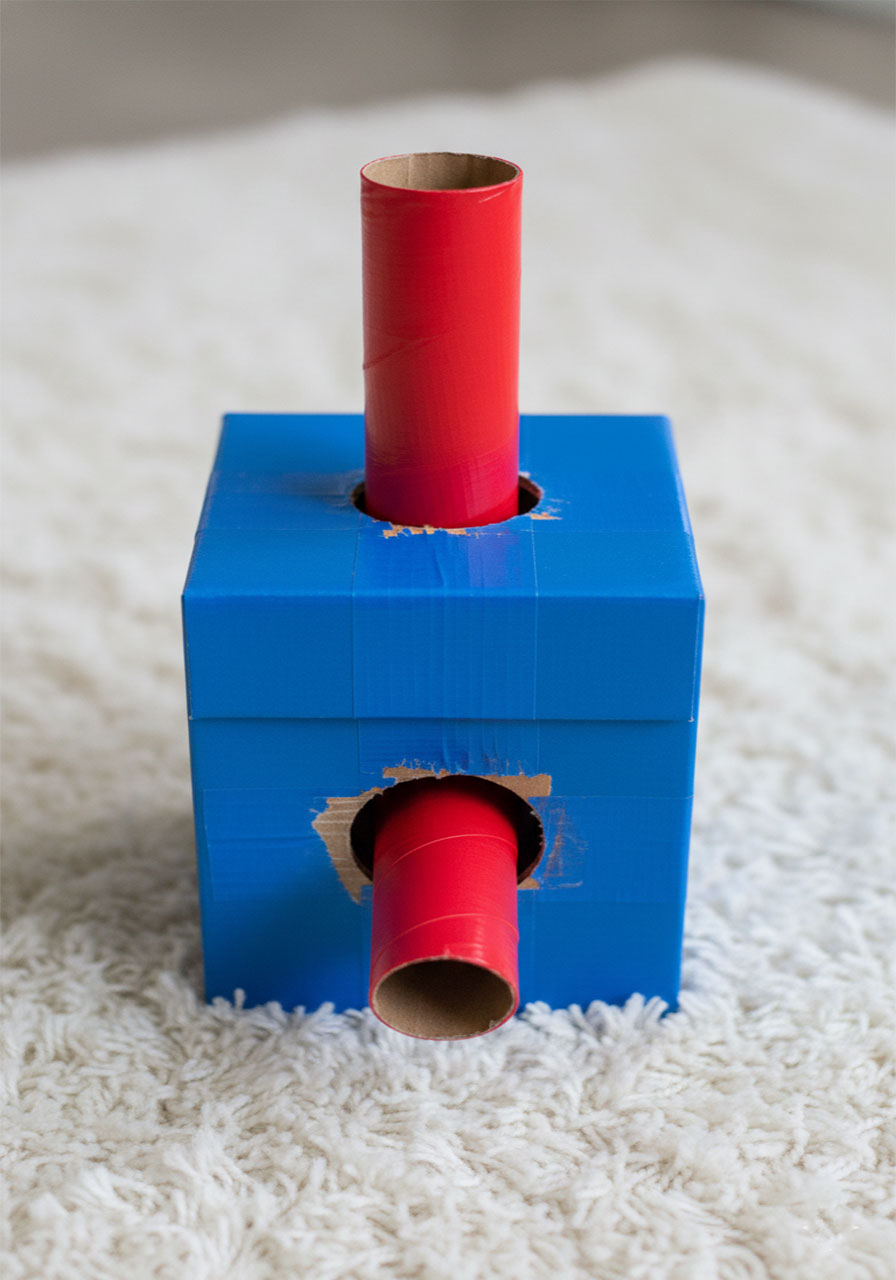 Homemade cardboard funnel tower with red paper towel tubes for pouring beans in a construction sensory bin