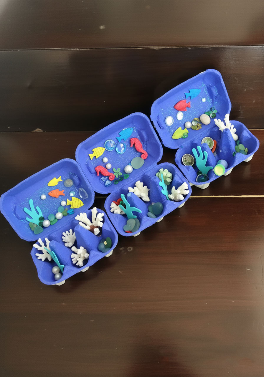 Completed egg carton ocean box craft for kids with painted sea creatures, seashells, and glitter glue ocean floor
