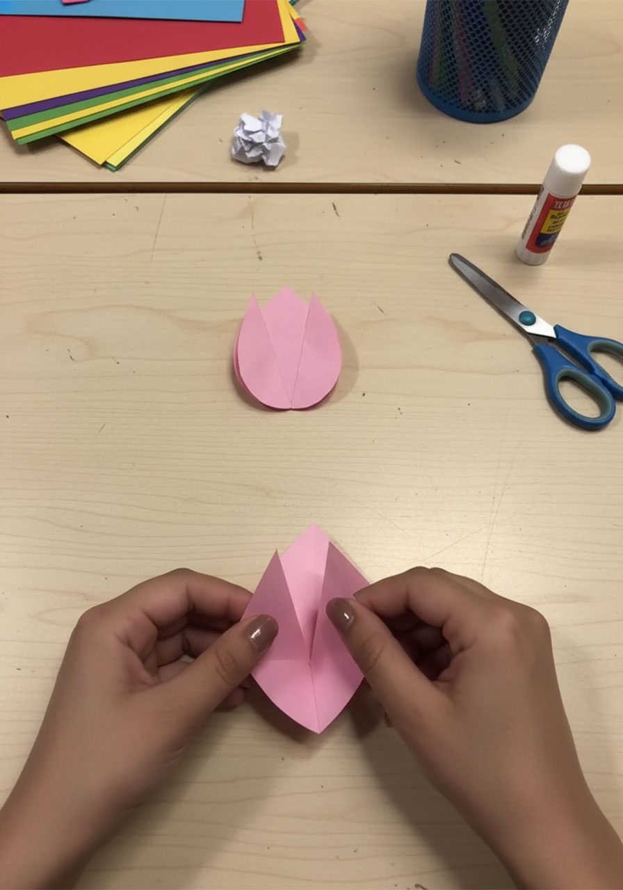 Step-by-step flat lay showing how to fold a 3D paper tulip for a DIY Mother's Day bouquet card, five stages from flat square to finished flower step1d