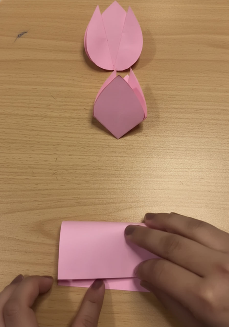 Step-by-step flat lay showing how to fold a 3D paper tulip for a DIY Mother's Day bouquet card, five stages from flat square to finished flower step1g