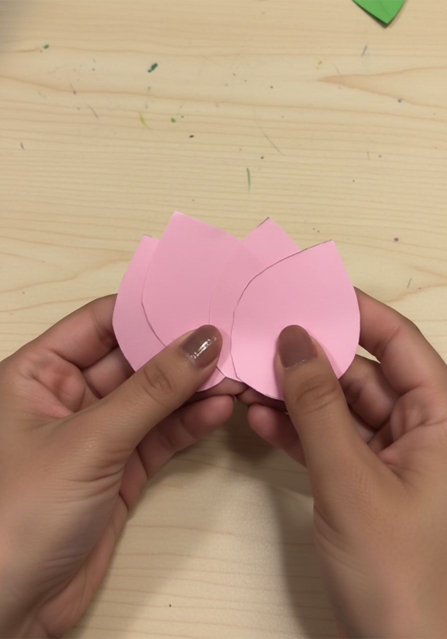 Step-by-step flat lay showing how to fold a 3D paper tulip for a DIY Mother's Day bouquet card, five stages from flat square to finished flower step1k