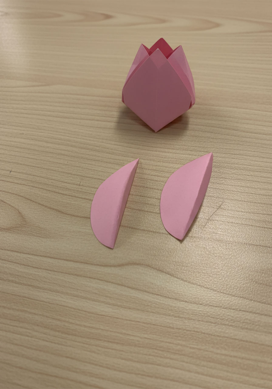 Step-by-step flat lay showing how to fold a 3D paper tulip for a DIY Mother's Day bouquet card, five stages from flat square to finished flower step1l