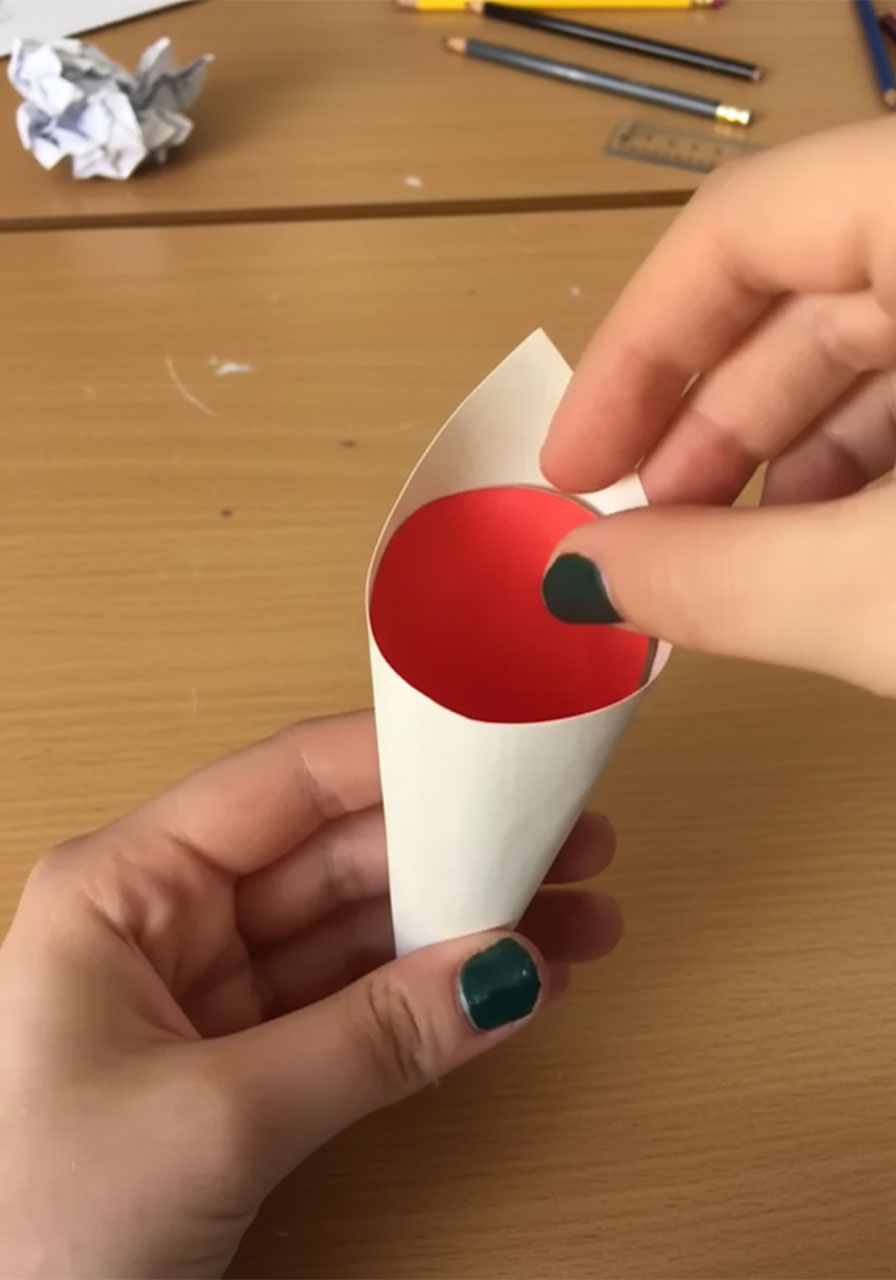 Two hands rolling white cardstock into a cone shape for a DIY paper rose bouquet, step 1 of the tutorial step1d