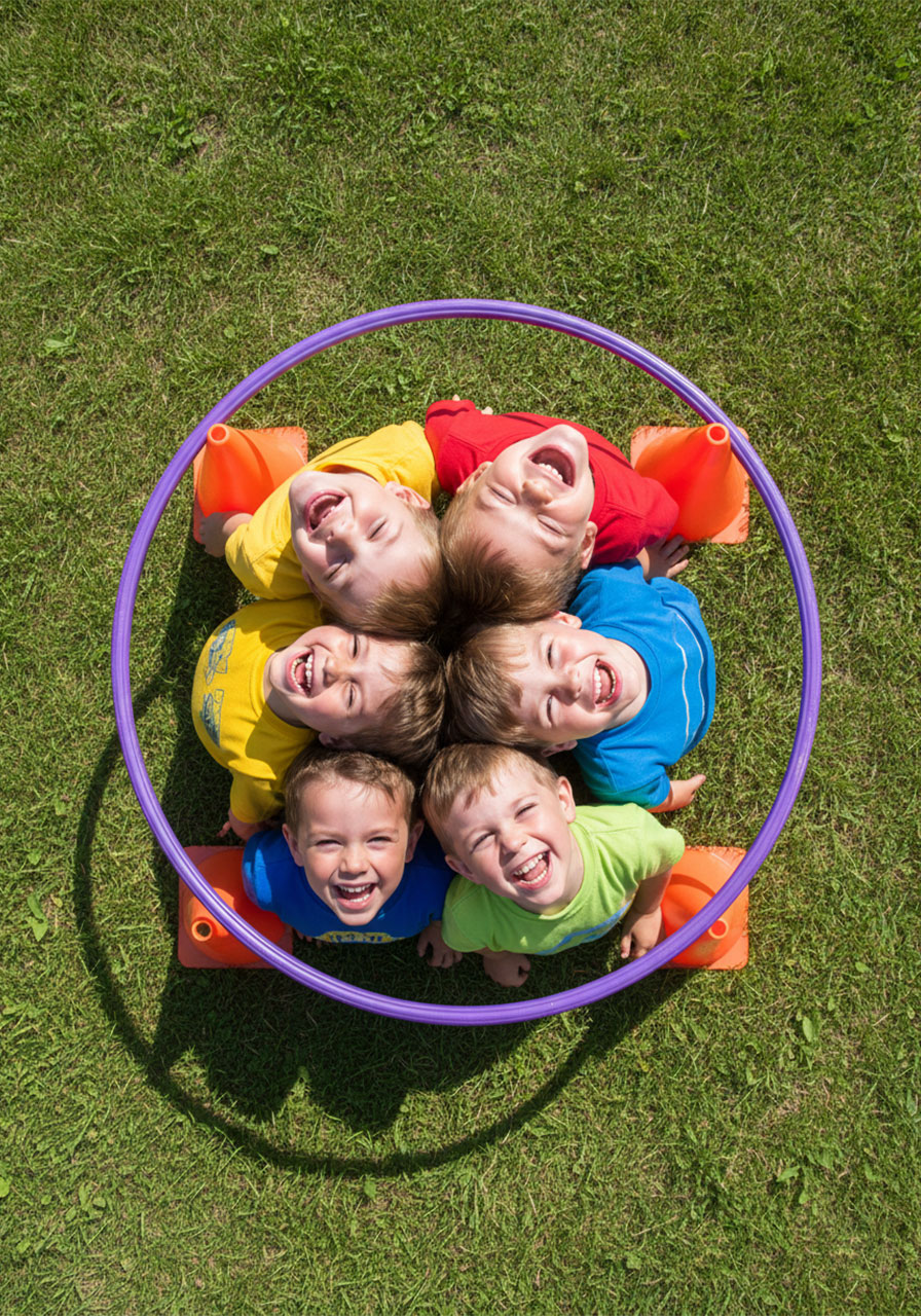 Overhead view of multiple children packed together inside a hula hoop during the cooperative Rabbit Hole game