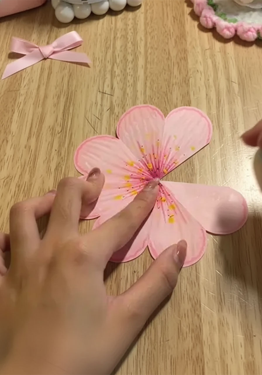 Shaping painted paper flower into 3D cone shape by cutting one petal and overlapping adjacent petals with glue step3a