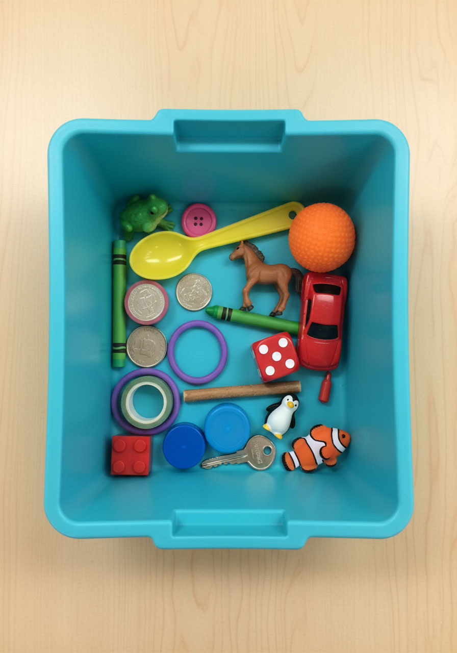 Bin of small household objects and toys used for a muffin tin letter sounds beginning sounds sorting activity for kids