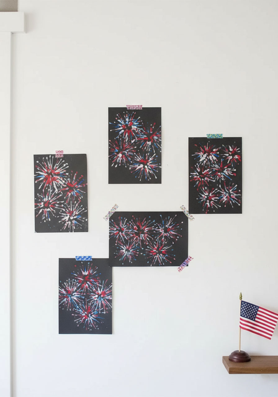 Five completed 4th of July kids firework paintings hung as patriotic wall decor in bright white living room