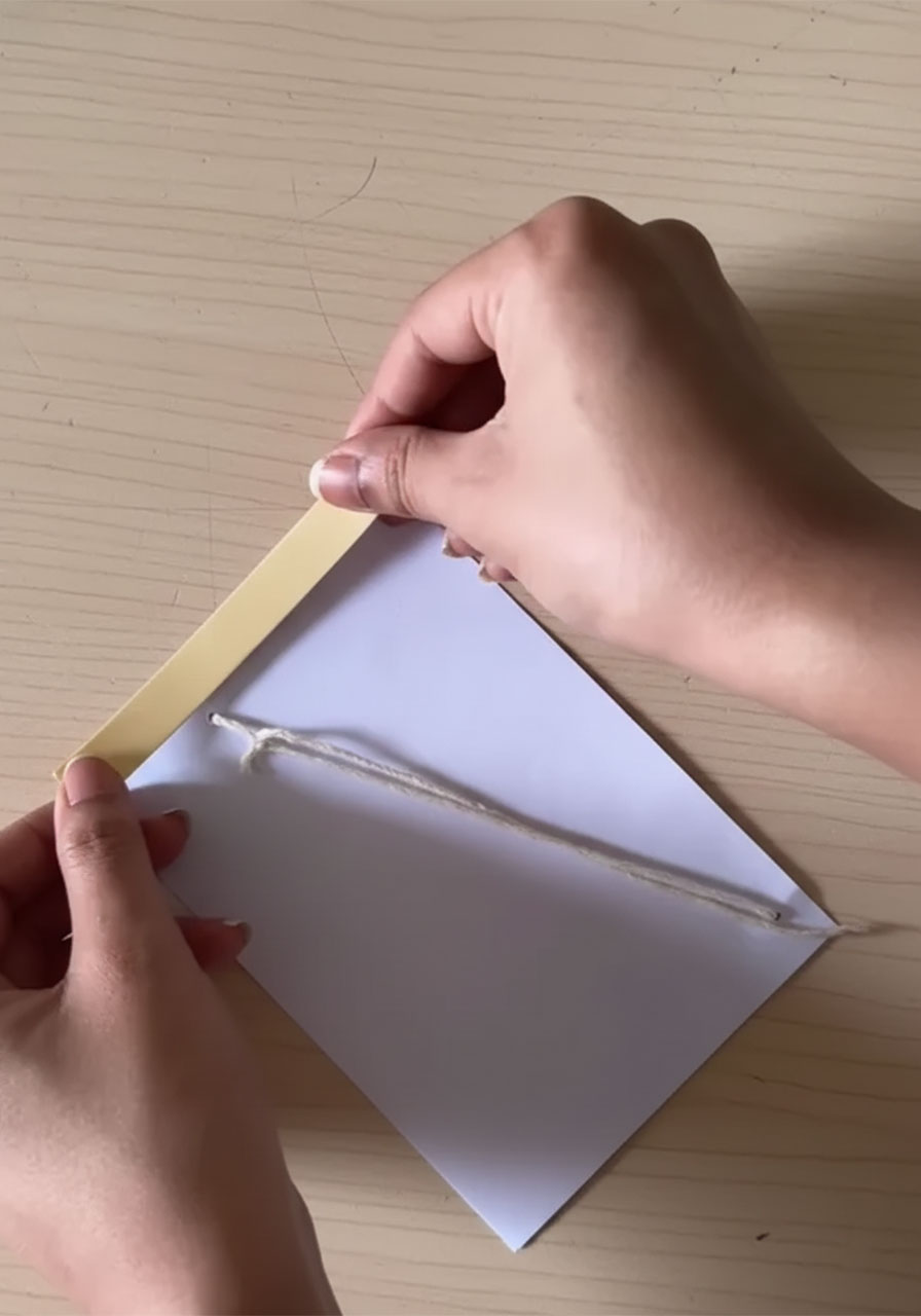 Back of DIY Father's Day card with double-sided foam tape applied to all four edges to create gap for pull-string mechanism step5a
