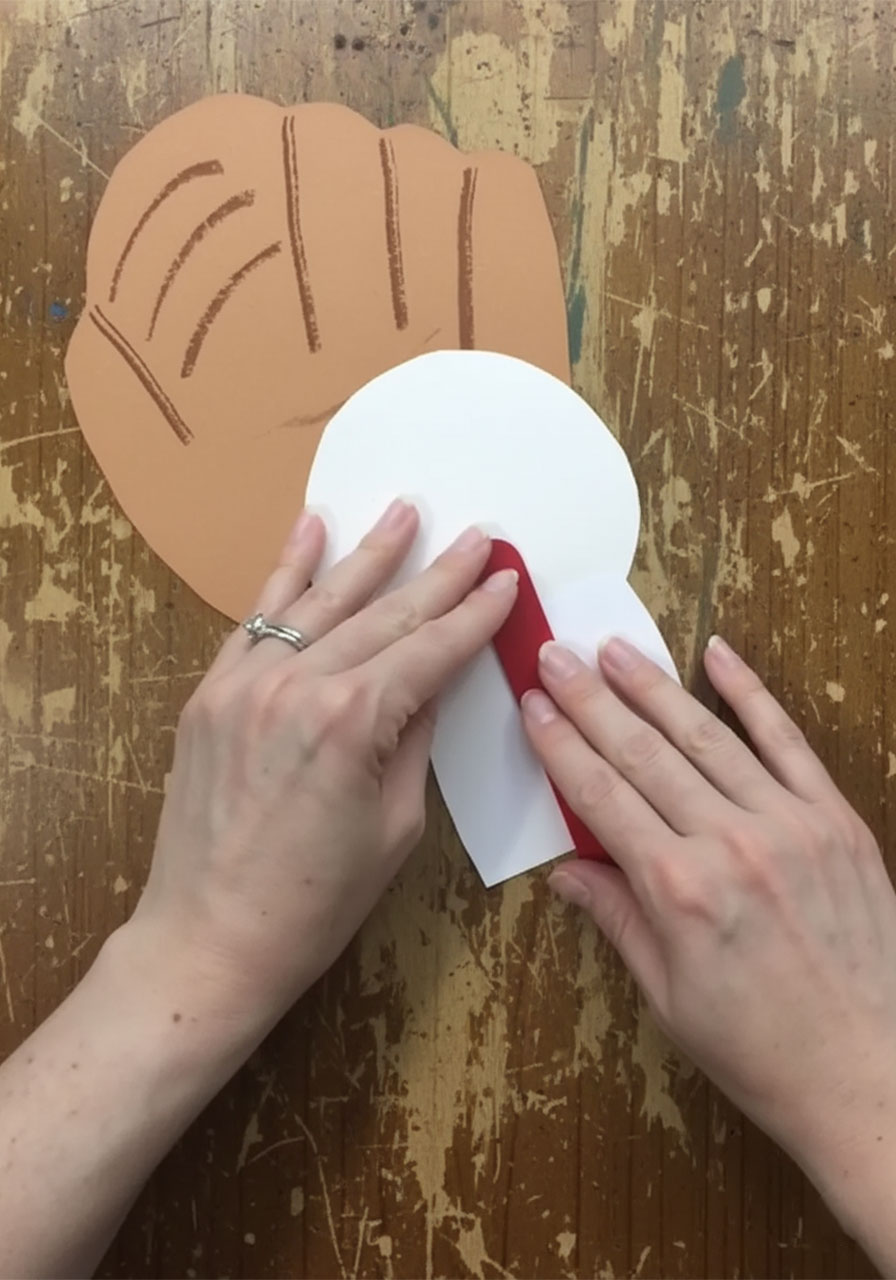 Step showing how to glue the red jumbo craft stick to the back of the baseball and photo for the pop-up mechanism