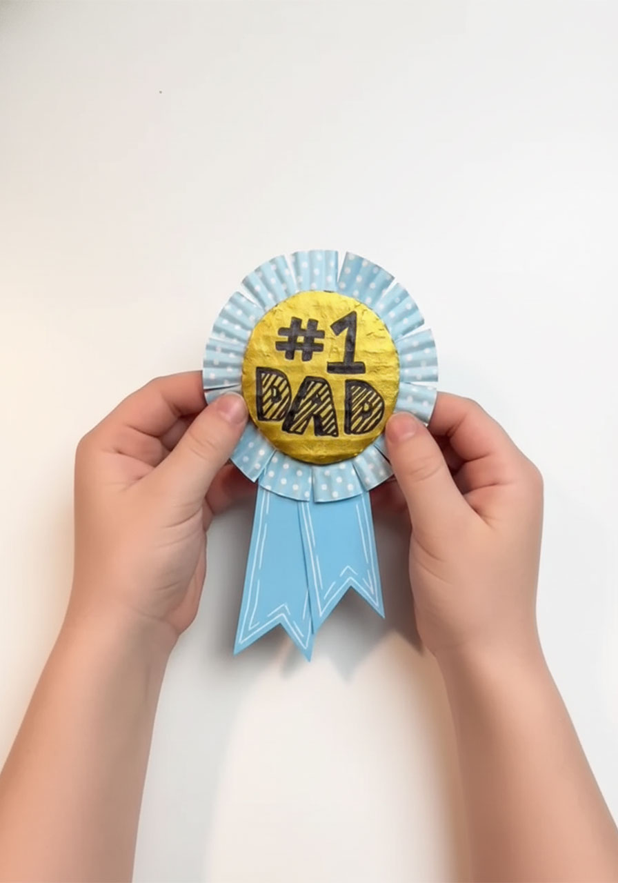 Finished DIY #1 Dad award ribbon for Father's Day made by kids using a gold cardboard circle, cupcake liner rosette, and blue paper ribbon tails