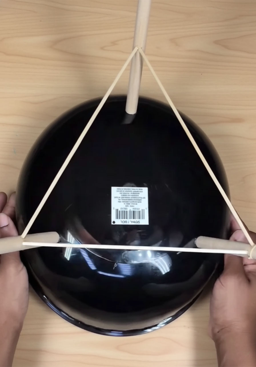 DIY kettle grill gift basket build step: attaching three short wooden dowel legs to the bottom of a black plastic bowl using E6000 glue in a tripod formation step3b