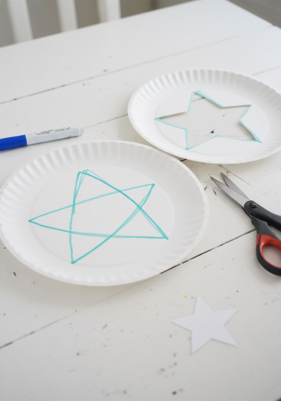 Paper plate with teal star drawn in marker next to finished star cutout with scissors showing how to make straw stamped 4th of July craft