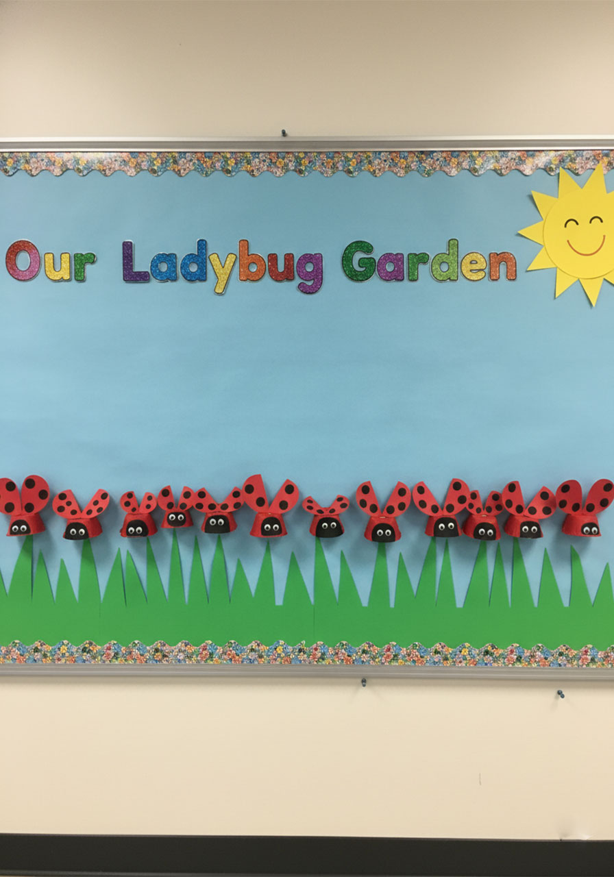Classroom spring bulletin board display featuring a row of handmade egg carton ladybug crafts made by kids, perfect for preschool and kindergarten
