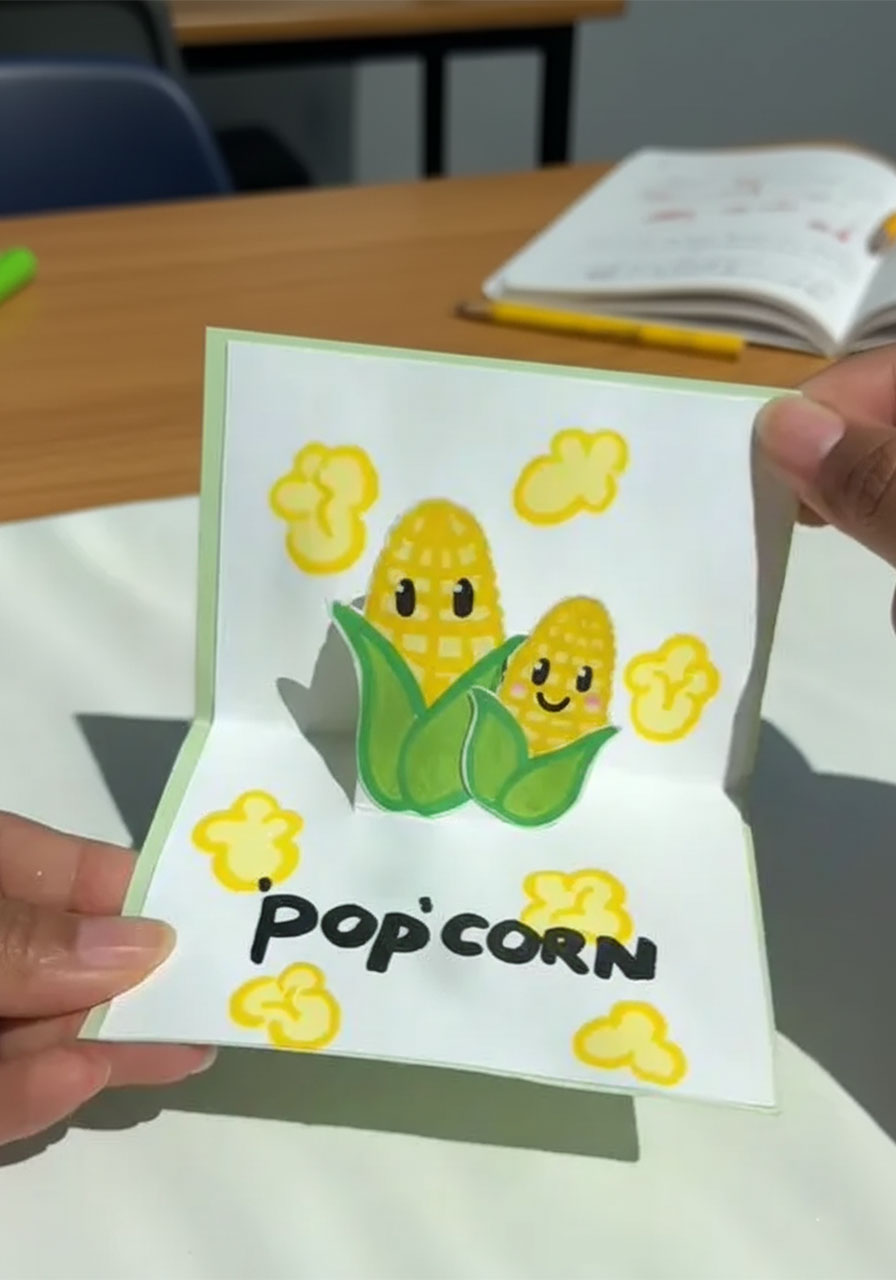 Finished handmade Father's Day pop-up card with cute corn characters and "Pop-Corn" joke inside b