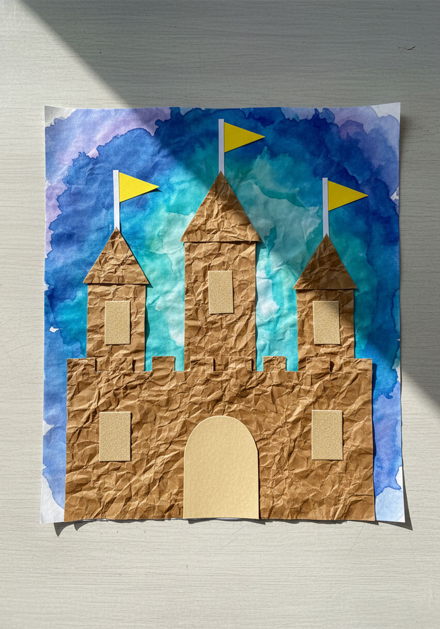 Completed sandcastle texture collage art project made from crumpled brown paper bags with yellow flags and watercolor sky background