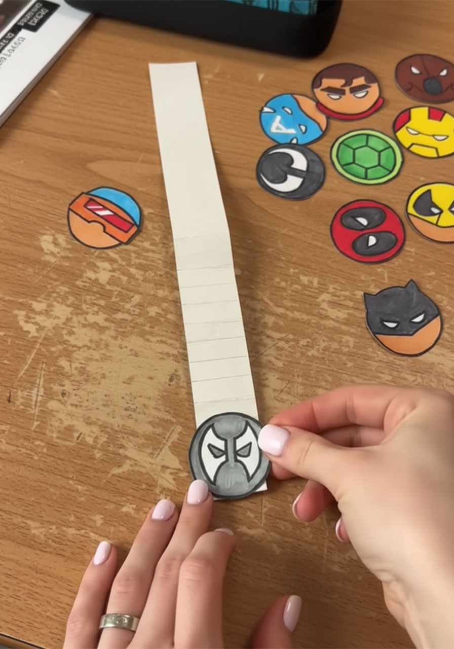 Gluing colorful superhero circle cutouts onto each fold of the accordion strip for a DIY Father's Day pop-up card phase 2 step6