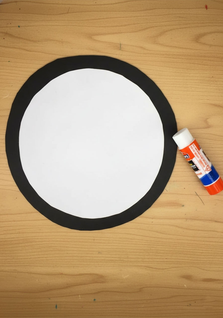 Hands gluing white cardstock circle onto black circle to create the inside of a Father's Day grill card