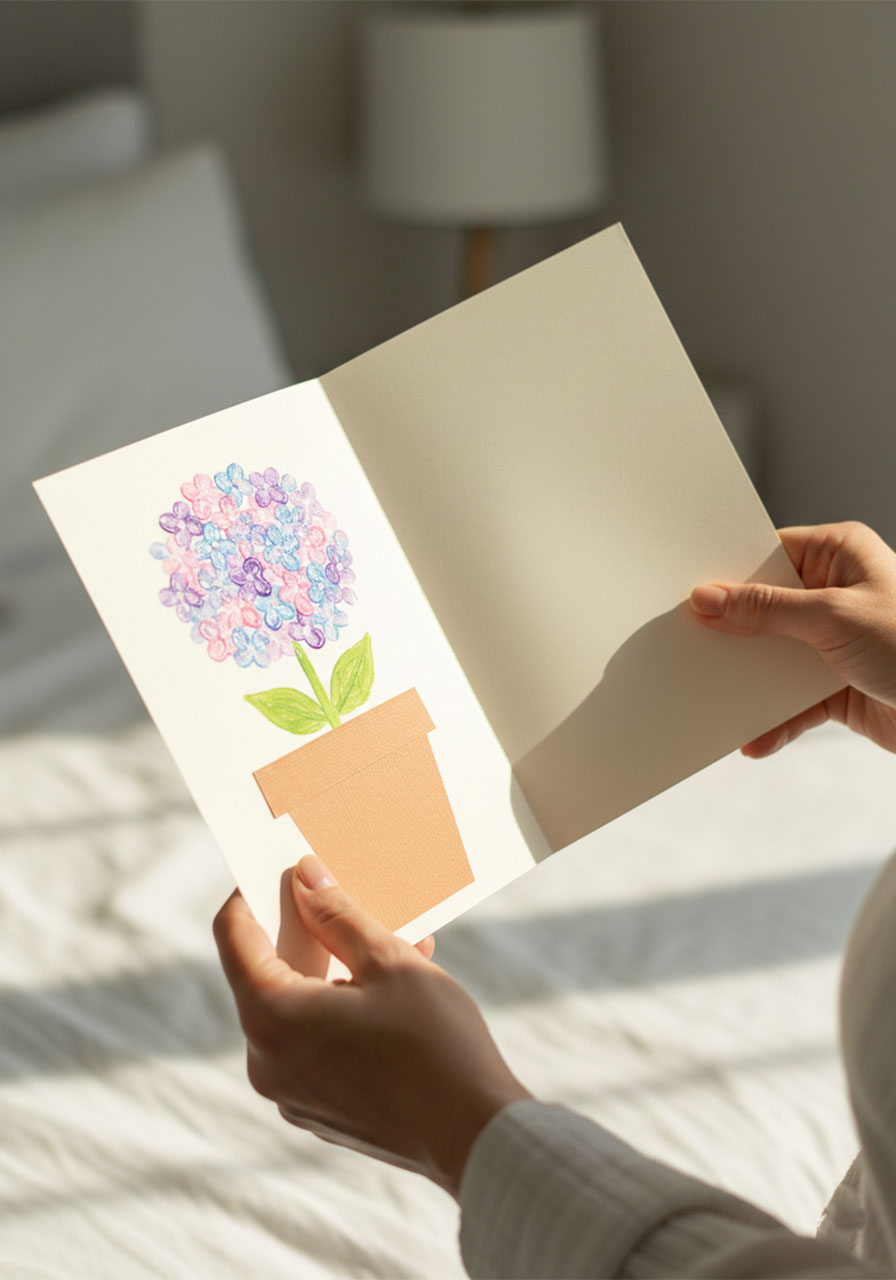 Adult hands holding finished handmade Mother's Day card with dotted pastel hydrangea painting mounted on cream cardstock as a heartfelt gift