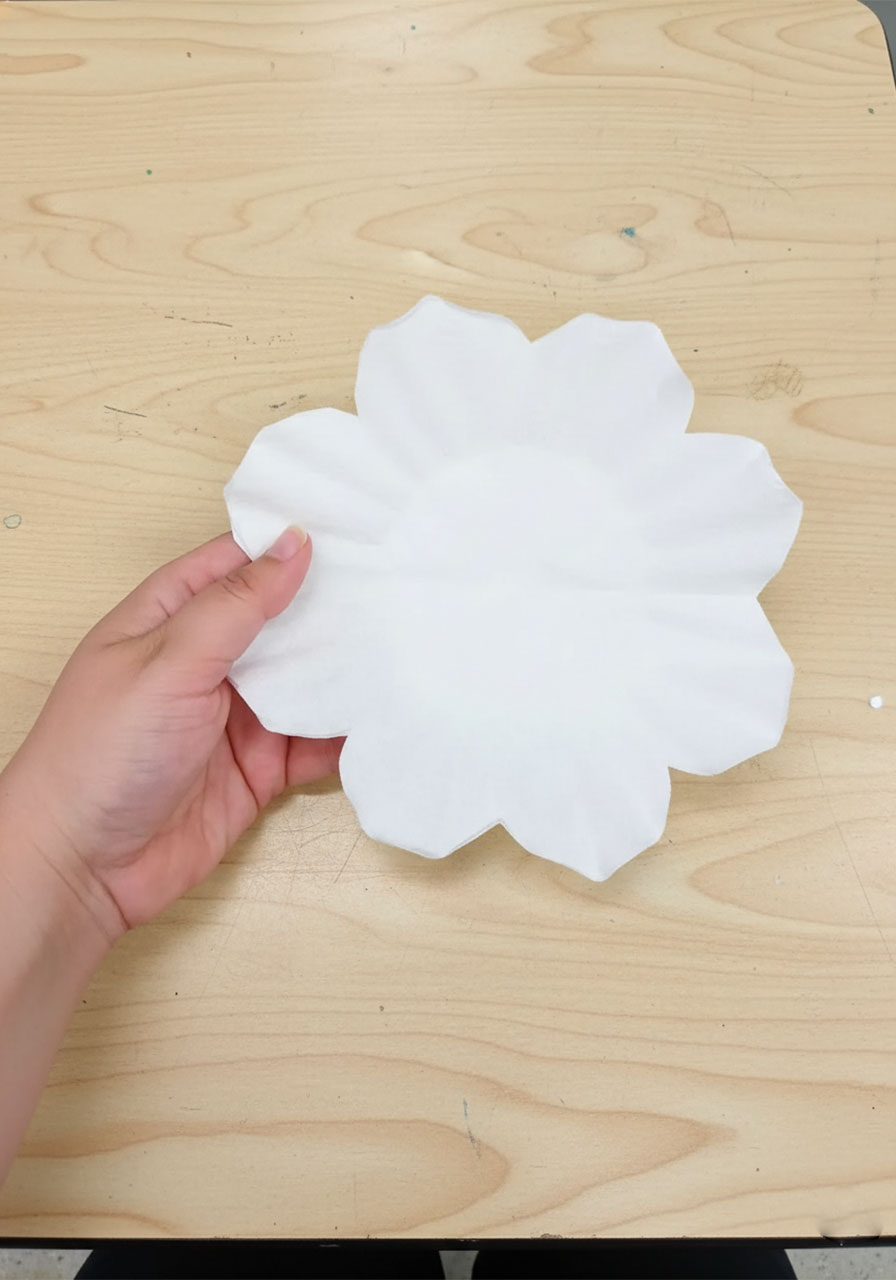 Step-by-step photos showing how to fold and cut coffee filters into a rose petal shape for DIY coffee filter roses step1c