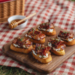 Million dollar bacon crostini with candied bacon, goat cheese, and honey drizzle on a wooden serving board