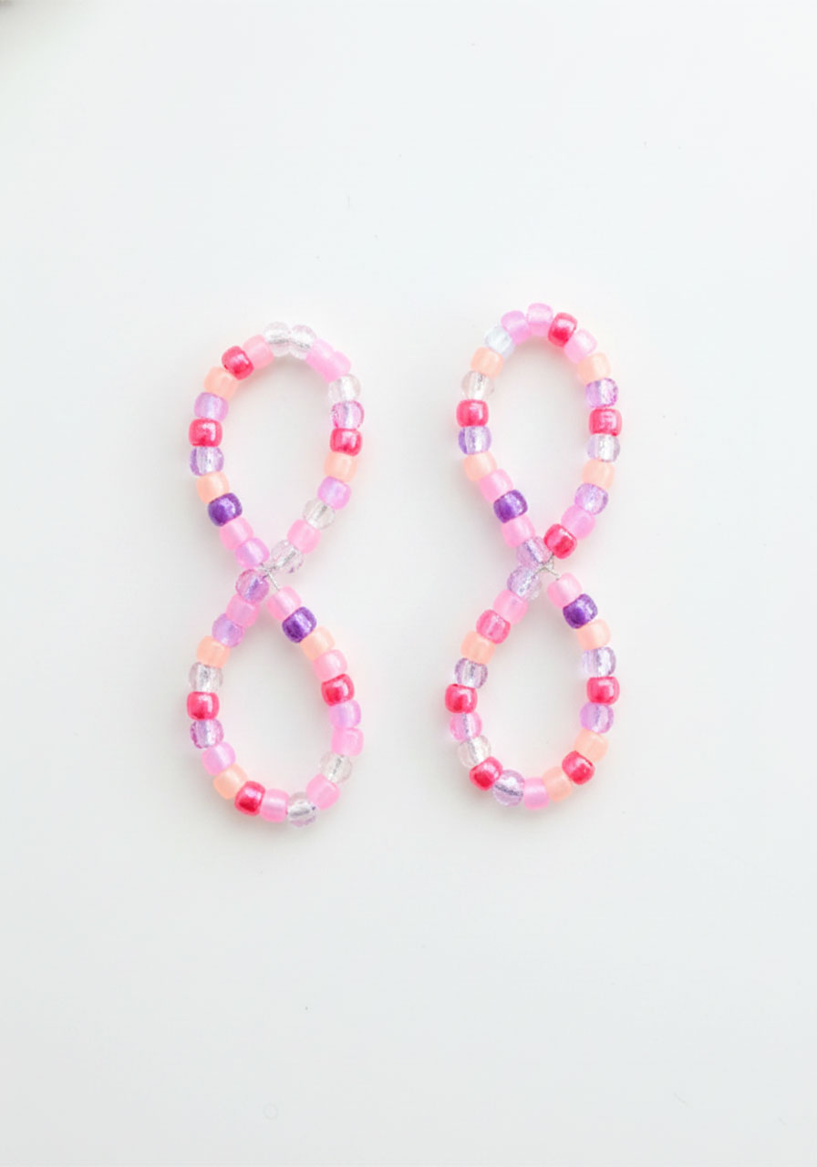 Two completed figure-eight shaped beaded pipe cleaner pieces side by side showing finished butterfly wing shapes ready for assembly