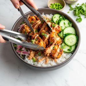Building a bang bang chicken bowl — layering rice, chicken, and fresh vegetables step by step