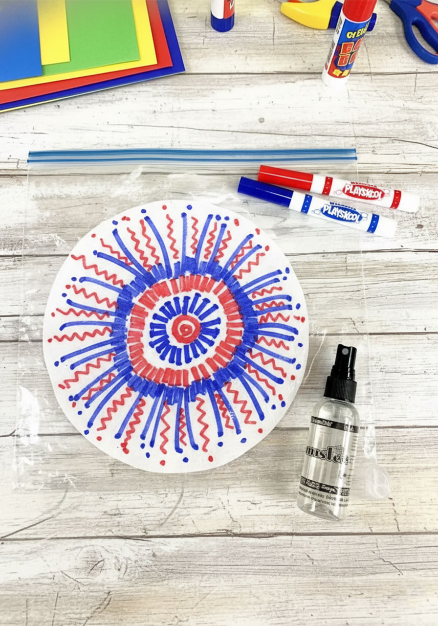 Child coloring a round coffee filter with red washable marker in a bold starburst fireworks pattern — Step 1 of the coffee filter watercolor fireworks craft