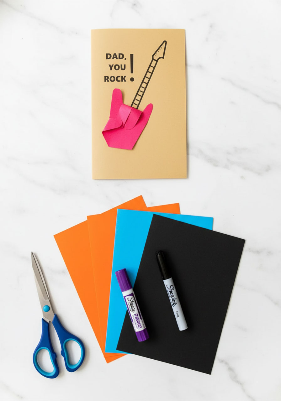 Pinterest image of Dad Rocks handprint guitar Father's Day card craft with supplies on white marble surface