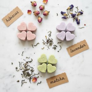 Homemade colored sugar cube variations in pink hibiscus, lavender butterfly pea flower, and matcha green arranged on marble