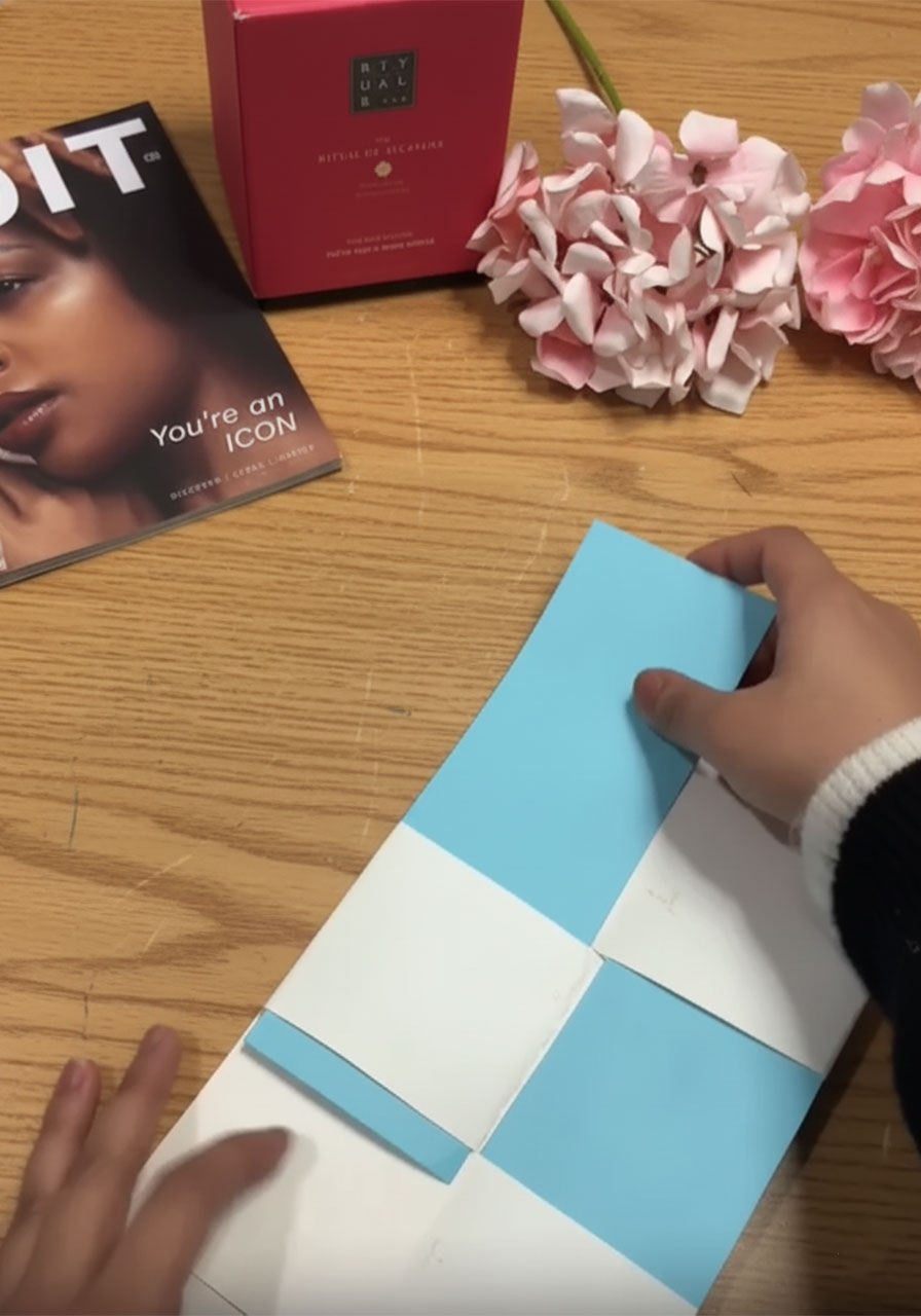 Weaving sky blue paper strips through white paper slits to create the checkerboard magic reveal pattern for the Father's Day flip card STEP4C