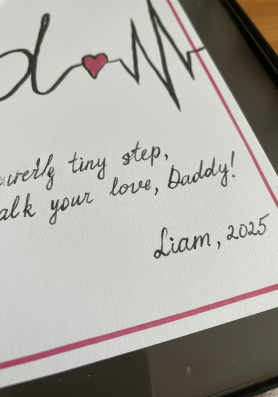Close-up of handwritten message on Father's Day footprint art reading With every tiny step I walk in your love Daddy