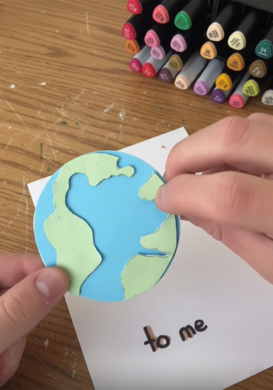 Foam adhesive tape squares on the back of a green paper continent creating the raised 3D effect on the handmade Father's Day globe card step5d