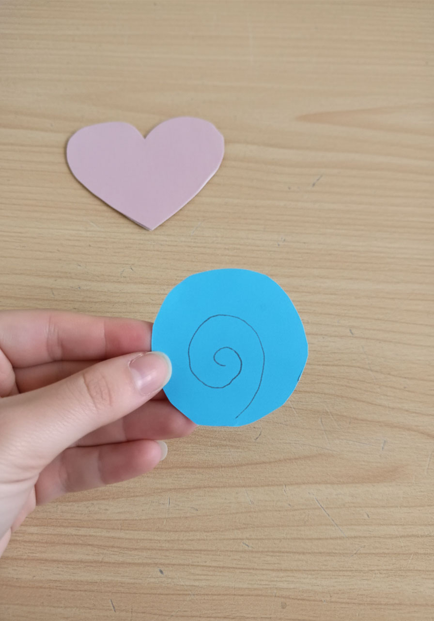 Hands rolling a cut paper spiral strip around a thin stick to form a 3D paper rose — DIY paper rose bouquet tutorial step by step 2a