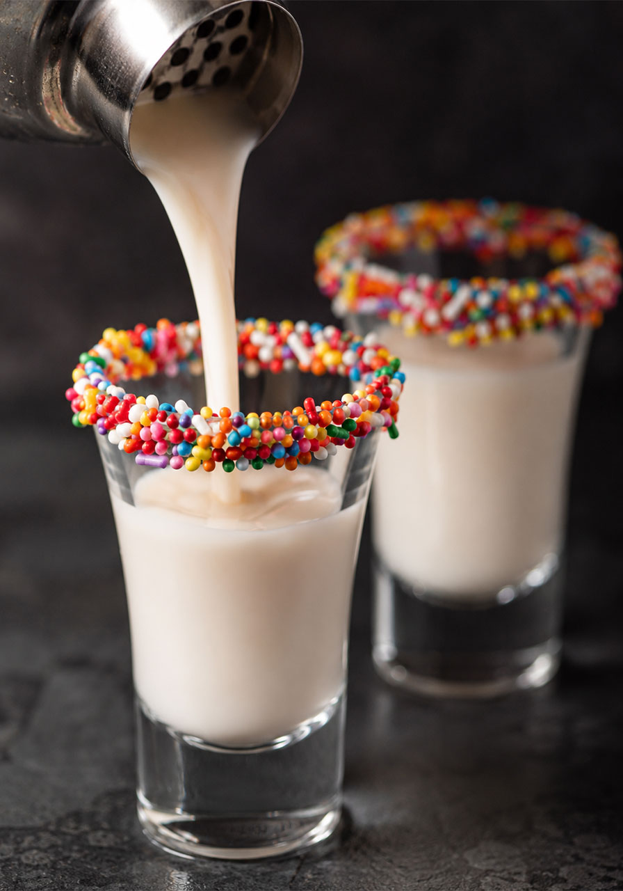 Birthday cake shots being poured into sprinkle-rimmed shot glasses for 21st birthday party