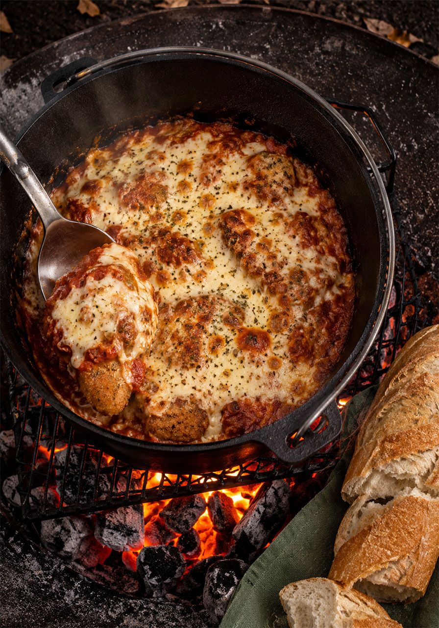 3-ingredient chicken parm casserole with golden melted mozzarella bubbling in a camp oven over campfire coals