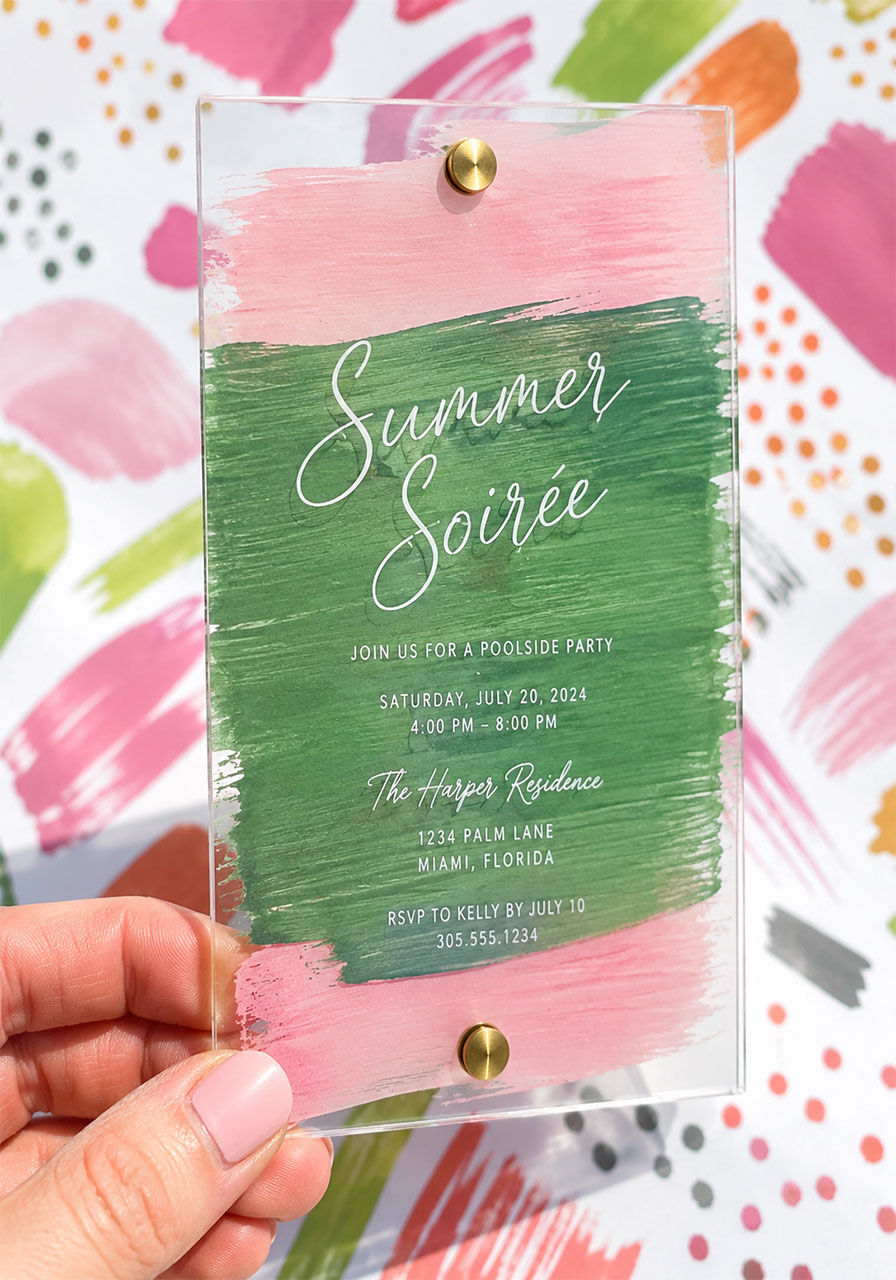 Close-up of transparent acrylic summer soirée invitation card with watercolor brushstrokes and white calligraphy script