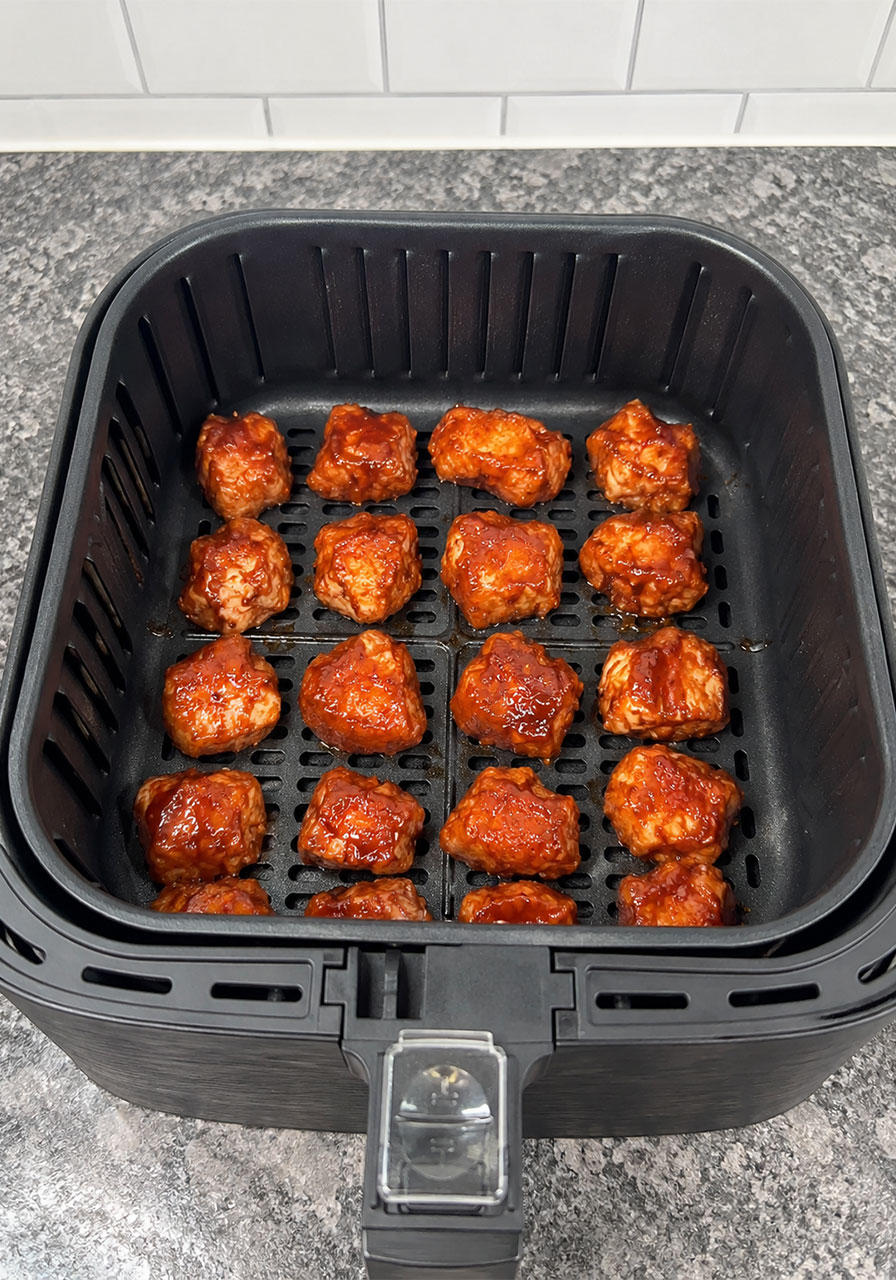 Marinated chicken bites arranged in a single layer in an air fryer basket