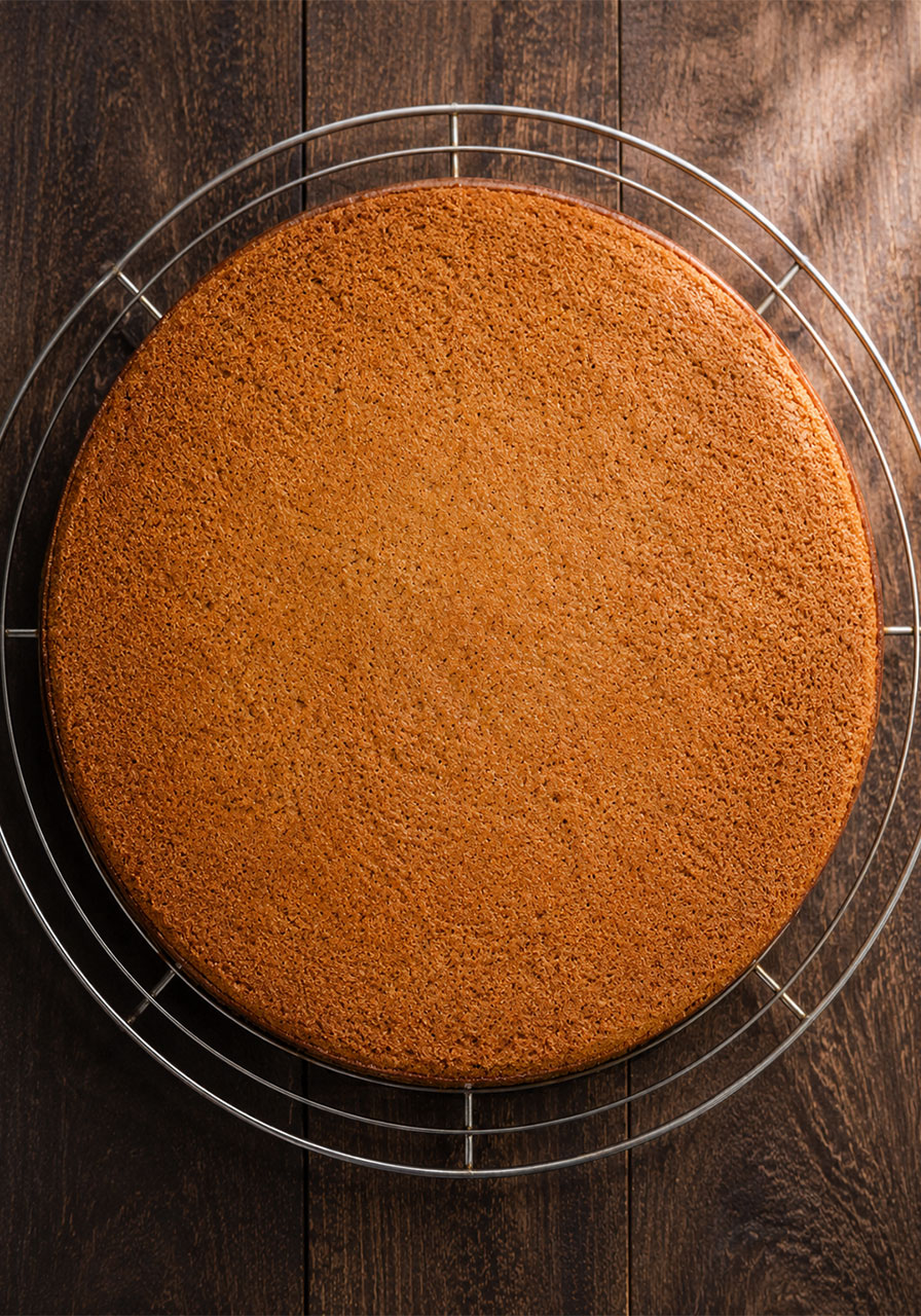 Perfectly flat baked brown sugar chai cake layer cooling on a wire rack after using cake strips